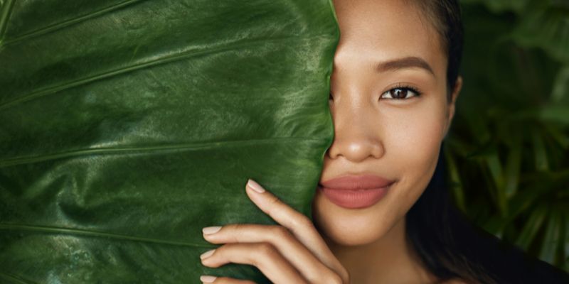 Woman behind large green leaf